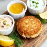 Crab cake sauce recipe on a wooden board with three signature sauces: lemon-garlic aioli, honey-mustard, and classic rémoulade. the ultimate trio for elevating your seafood dish