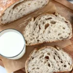 Sourdough cinnamon bread sliced on wooden board with glass of milk