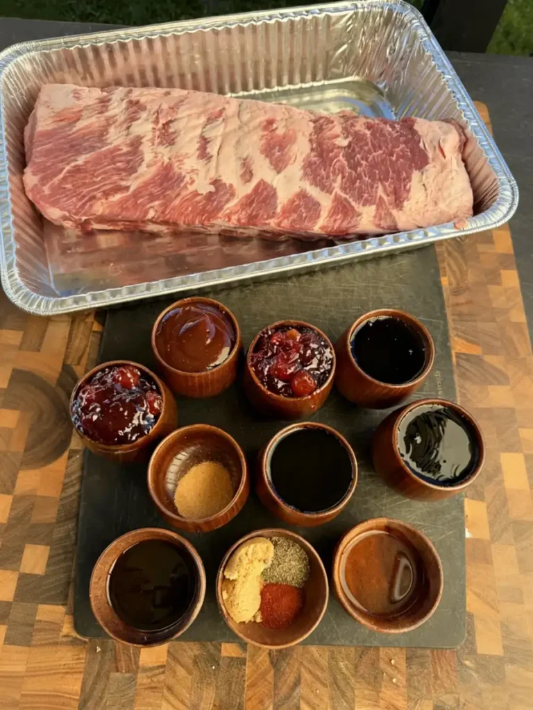 Raw baby back ribs and ingredients for Cherry Cola Smoked Party Ribs on cutting board
