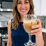 Mounjaro natural receita dra. andreia em uma cozinha clara, com uma mulher segurando um copo com bebida amarelo-dourada.