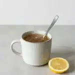 receita de gelatina do Dr. Gupta: bebida quente em caneca branca com limão e colher.